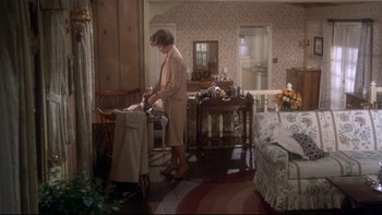 Movie still from “Same Time, Next Year” (1978), directed by Robert Mulligan – A woman standing in a living room next to a couch; Wide shot, High angle
