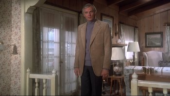 Movie still from “Same Time, Next Year” (1978), directed by Robert Mulligan – A man standing in a living room wearing a suit; Medium shot, Low angle