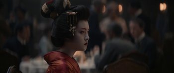 A geisha is standing in front of a group of people