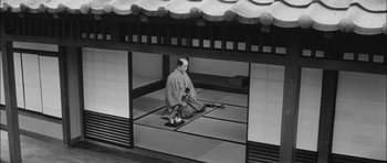 Movie still from “Samurai Rebellion” (1967), directed by Masaki Kobayashi – A man sitting on the ground in front of a building; Wide shot, High angle