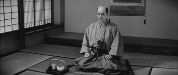 Movie still from “Samurai Rebellion” (1967), directed by Masaki Kobayashi – A man sitting on the ground in a kimono; Medium shot, High angle