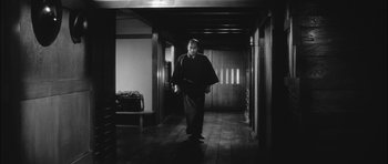 Movie still from “Samurai Rebellion” (1967), directed by Masaki Kobayashi – A black and white photo of a man walking in a hallway; Wide shot, Low angle