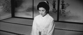 Movie still from “Samurai Rebellion” (1967), directed by Masaki Kobayashi – A young woman in a white kimono is standing in front of a wall; Medium shot, High angle