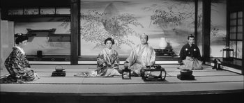 Movie still from “Samurai Rebellion” (1967), directed by Masaki Kobayashi – A man and a woman sitting on the ground in front of a painting; Wide shot, Low angle