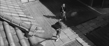 Movie still from “Samurai Rebellion” (1967), directed by Masaki Kobayashi – Two people are walking on the sidewalk with a broom; Extreme Wide shot, High angle