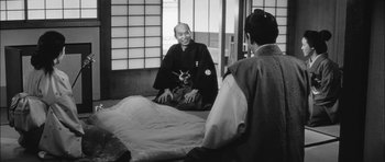 Movie still from “Samurai Rebellion” (1967), directed by Masaki Kobayashi – A man sitting on the ground in a room with another man; Medium shot, Over the shoulder angle