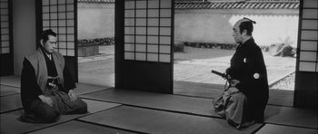 Movie still from “Samurai Rebellion” (1967), directed by Masaki Kobayashi – A black and white photo of a person holding a sword; Wide shot, Low angle