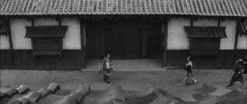 Movie still from “Samurai Rebellion” (1967), directed by Masaki Kobayashi – A man holding a sword in front of a building; Extreme Wide shot, High angle