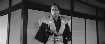 Movie still from “Samurai Rebellion” (1967), directed by Masaki Kobayashi – A black and white photo of a man holding a katana; Medium shot, Low angle
