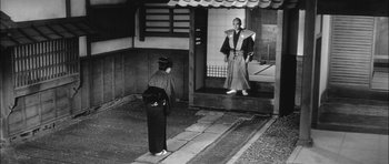 Movie still from “Samurai Rebellion” (1967), directed by Masaki Kobayashi – A man and a woman standing in front of a building; Wide shot, Low angle