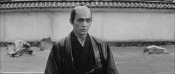 Movie still from “Samurai Rebellion” (1967), directed by Masaki Kobayashi – A black and white photo of a man with a shaved head; Close Up shot, Low angle