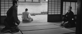 Movie still from “Samurai Rebellion” (1967), directed by Masaki Kobayashi – A man sitting on the ground in front of a building; Wide shot, High angle