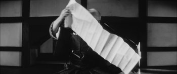 Movie still from “Samurai Rebellion” (1967), directed by Masaki Kobayashi – A man holding a sheet of paper in front of him; Medium shot, Low angle