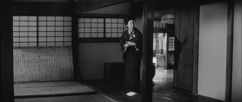 Movie still from “Samurai Rebellion” (1967), directed by Masaki Kobayashi – A woman dressed in traditional japanese clothing standing in front of a window; Wide shot, Low angle