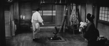 Movie still from “Samurai Rebellion” (1967), directed by Masaki Kobayashi – A man standing in front of an object in a room; Wide shot, High angle