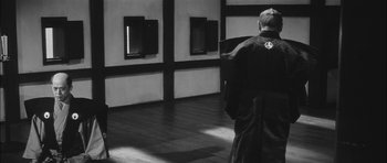 Movie still from “Samurai Rebellion” (1967), directed by Masaki Kobayashi – A man standing in front of a wall of windows in a room; Wide shot, Low angle