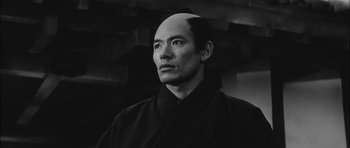 Movie still from “Samurai Rebellion” (1967), directed by Masaki Kobayashi – A black and white photo of a man with a bald head; Close Up shot, Low angle