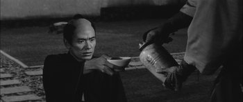 Movie still from “Samurai Rebellion” (1967), directed by Masaki Kobayashi – A man holding a bowl in front of another man; Medium shot, High angle