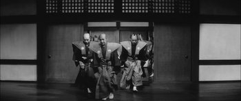 Movie still from “Samurai Rebellion” (1967), directed by Masaki Kobayashi – A group of men dressed in samurai garb in front of a building; Wide shot, Low angle