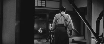 Movie still from “Samurai Rebellion” (1967), directed by Masaki Kobayashi – A man standing in front of an open fireplace; Medium shot, Low angle