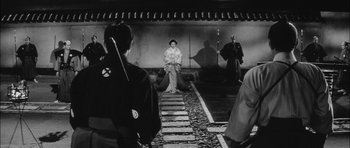 Movie still from “Samurai Rebellion” (1967), directed by Masaki Kobayashi – A man sitting on the ground in front of a group of people; Wide shot, Over the shoulder angle