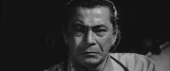 Movie still from “Samurai Rebellion” (1967), directed by Masaki Kobayashi – An older man with long black hair wearing a white shirt; Close Up shot, Low angle