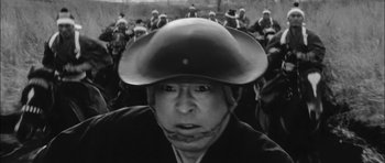 Movie still from “Samurai Rebellion” (1967), directed by Masaki Kobayashi – A man wearing a cowboy hat in front of a group of people; Close Up shot, Low angle