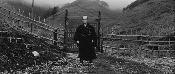 Movie still from “Samurai Rebellion” (1967), directed by Masaki Kobayashi – A man standing in front of a wooden fence; Wide shot, Low angle