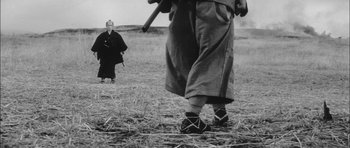 Movie still from “Samurai Rebellion” (1967), directed by Masaki Kobayashi – A man holding a stick in a field; Wide shot, Low angle