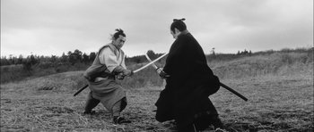 Movie still from “Samurai Rebellion” (1967), directed by Masaki Kobayashi – Two men in traditional japanese garb fighting with swords in a field; Medium shot, Low angle