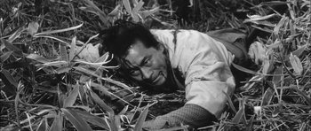 Movie still from “Samurai Rebellion” (1967), directed by Masaki Kobayashi – A man in a white shirt is laying in the grass; Medium shot, High angle