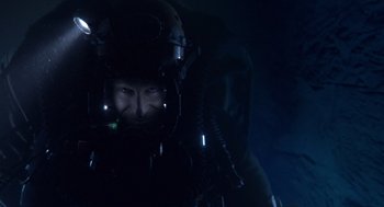 Movie still from “Sanctum” (2011), directed by Alister Grierson – A man wearing a helmet and goggles in a dark room; Close Up shot, Overhead angle