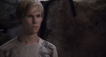 Movie still from “Sanctum” (2011), directed by Alister Grierson – A young man with blonde hair and blue eyes stares into the camera; Close Up shot, Over the shoulder angle