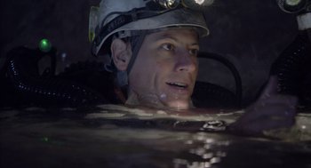 Movie still from “Sanctum” (2011), directed by Alister Grierson – A man wearing a hard hat in a body of water at night; Close Up shot, Overhead angle