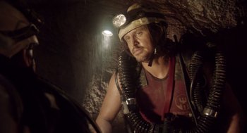Movie still from “Sanctum” (2011), directed by Alister Grierson – A man with a helmet and a light on his head in a cave; Medium shot, Low angle