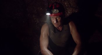 Movie still from “Sanctum” (2011), directed by Alister Grierson – A man with a helmet on his head is sitting in a cave; Medium shot, Low angle