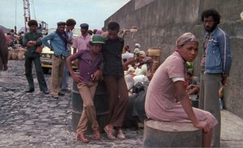 Movie still from “Sans Soleil” (1983), directed by Chris Marker – A group of people standing on top of a stone road; Wide shot, High angle