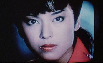 Movie still from “Sans Soleil” (1983), directed by Chris Marker – A woman's face in a red shirt; Close Up shot, High angle