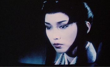 Movie still from “Sans Soleil” (1983), directed by Chris Marker – A woman's face in front of a television screen; Close Up shot, Low angle