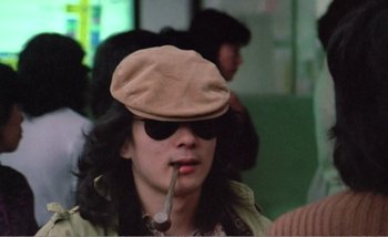 Movie still from “Sans Soleil” (1983), directed by Chris Marker – A man wearing a hat and smoking a pipe; Close Up shot, Low angle