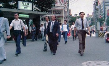 Movie still from “Sans Soleil” (1983), directed by Chris Marker – A group of people walking down a street; Wide shot, Low angle