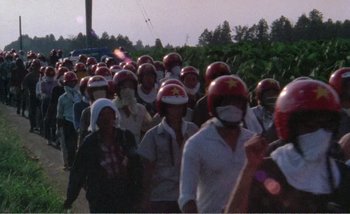 Movie still from “Sans Soleil” (1983), directed by Chris Marker – A large group of people wearing red helmets; Extreme Wide shot, High angle