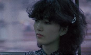 Movie still from “Sans Soleil” (1983), directed by Chris Marker – A woman with a black hair and a black shirt; Close Up shot, High angle