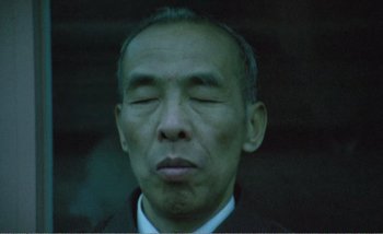 Movie still from “Sans Soleil” (1983), directed by Chris Marker – An older man with his eyes closed; Close Up shot, Low angle
