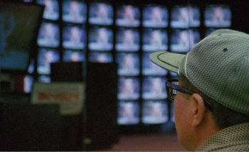 Movie still from “Sans Soleil” (1983), directed by Chris Marker – A man wearing a hat looking at a television screen; Extreme Close Up shot, Over the shoulder angle