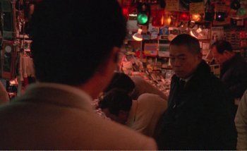 Movie still from “Sans Soleil” (1983), directed by Chris Marker – A group of people sitting at a table in a restaurant; Medium shot, Over the shoulder angle