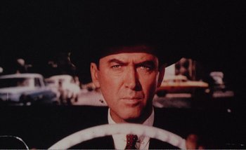 Movie still from “Sans Soleil” (1983), directed by Chris Marker – A person wearing a suit and hat; Close Up shot, Low angle