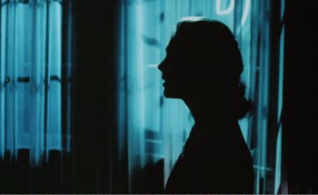 Movie still from “Sans Soleil” (1983), directed by Chris Marker – The silhouette of a woman is shown against a blue background; Close Up shot, Over the shoulder angle