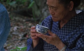 Movie still from “Sans Soleil” (1983), directed by Chris Marker – An older woman is holding a cup in her hands; Close Up shot, High angle