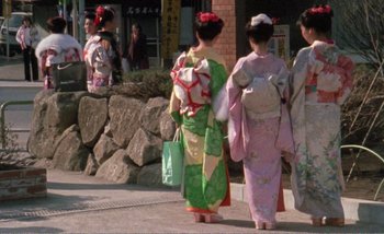Movie still from “Sans Soleil” (1983), directed by Chris Marker – A group of women in kimonos walking down a street; Wide shot, High angle
